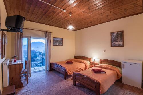 a bedroom with two beds and a balcony at To Aidoni in Karpenision