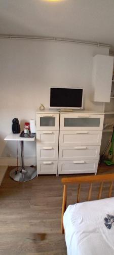 - une chambre avec une télévision et une commode blanche dans l'établissement París 10, à Paris