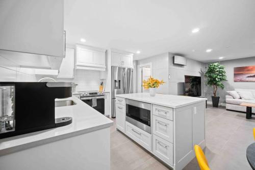 a kitchen with white cabinets and a living room at NEW! - Bright Modern Entire Unit KING BED! in Portland
