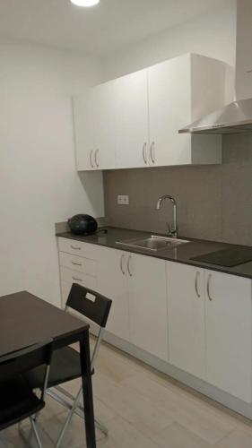 a kitchen with white cabinets and a table and a sink at Cozy studio with mountain view - 35 m² in La Ràpita in Sant Carles de la Ràpita