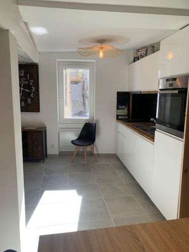 - une cuisine avec des placards blancs et une chaise dans l'établissement Appartement centre du village, à Saint-Étienne-de-Tinée
