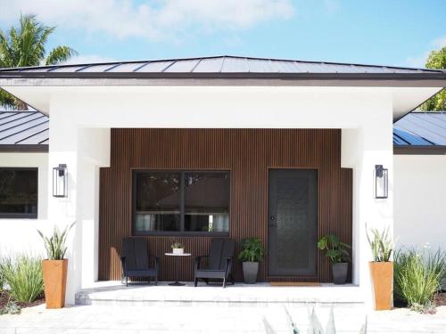 Ein Haus mit einer Veranda mit Stühlen und einem Tisch in der Unterkunft NEW Luxury Mellow Marlin w Pool Jupiter FL in Jupiter