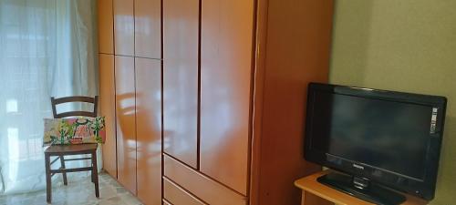 sala de estar con TV y armario de madera en A casa di Naty, en Gravina di Catania