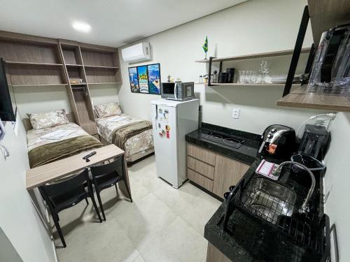 a small room with a kitchen with a bed and a refrigerator at Flat Studio Alto Padrão em Patos de Minas in Patos de Minas