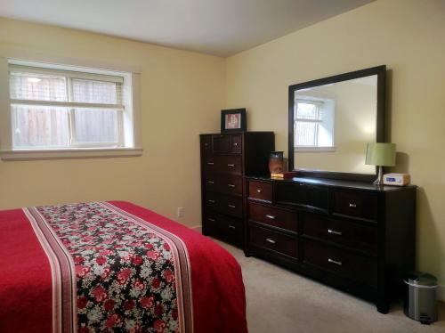 a bedroom with a bed and a dresser with a mirror at Angela's Private Suites in Surrey