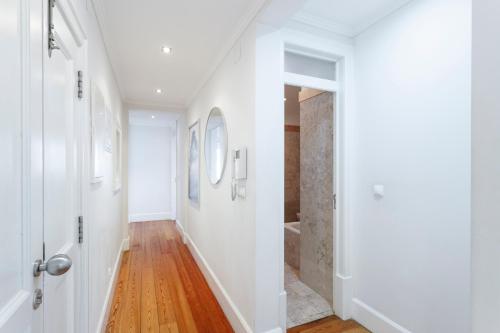 a hallway with white walls and wood floors and a bathroom at Madalena EXCLUSIVE SUITES in Lisbon