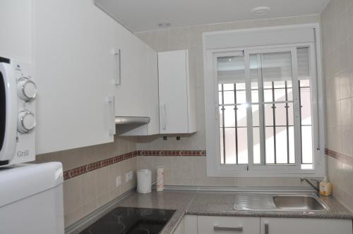 a kitchen with white cabinets and a sink and a window at Atiko Welcome in Arcos de la Frontera