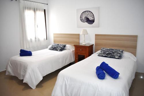 two beds in a bedroom with blue pillows on them at Almina in Corralejo