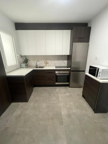 a kitchen with white cabinets and a sink and a microwave at Apartamento Cambil in Baeza