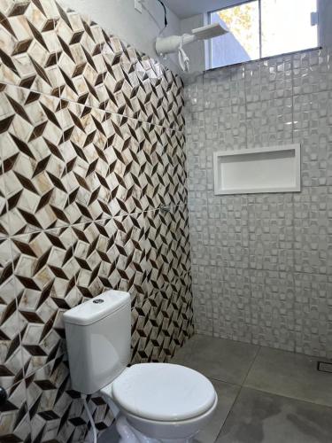 a bathroom with a toilet and a geometric wall at Residencial Jasmim quarto Standard 01 in Palmas