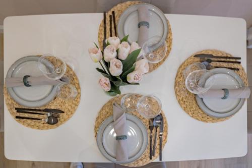 a table with plates and glasses and a vase of flowers at Appartamento Visconti by Rhospitality it in Rho