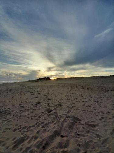 a beach with footprints in the sand and a cloudy sky at Aroma de mar casas en alquiler vacacional con hermosa piscina in Sauce de Portezuelo