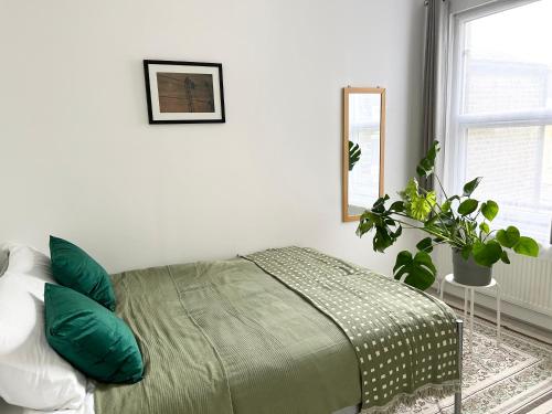a bedroom with a bed with green pillows and a mirror at London Serviced Accommodation near Tottenham Hotspurs Football Stadium Great for Contractors in London