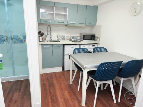 une cuisine avec des placards bleus et une table et des chaises blanches dans l'établissement Paris maison-4min à Métro7-18min au centre de Paris, à Villejuif