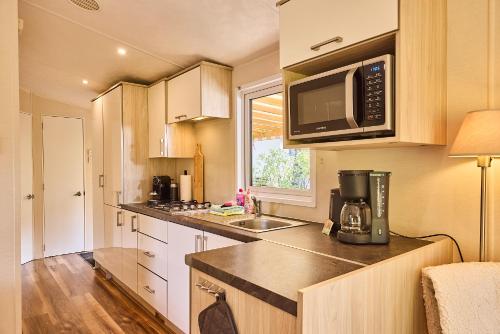a small kitchen with a microwave and a sink at Chalet huisje Bella op de Veluwe max 2 volwassene in Beekbergen