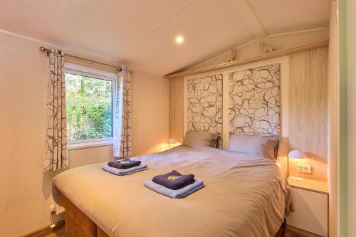 a bedroom with a bed with two towels on it at Chalet huisje Bella op de Veluwe max 2 volwassene in Beekbergen