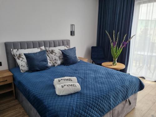 Una cama con un edredón azul con un pequeño cartel. en SkyHel Apartament 202, en Hel