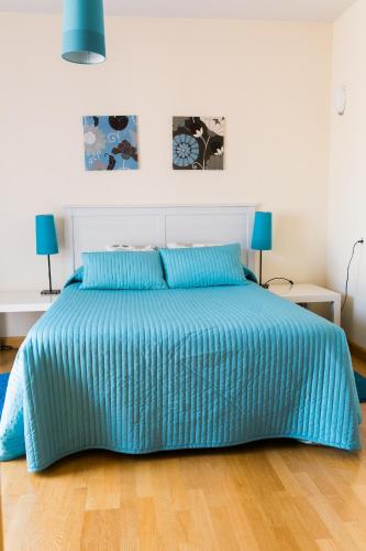 a bed with a blue comforter in a bedroom at Aticos La Aliseda by Valdesierra in Béjar