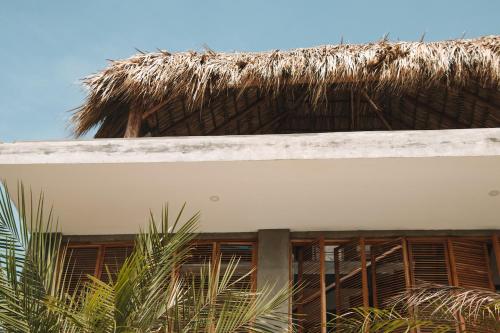 SalinasWaves & Wifi - Coworking & Coliving Space in Popoyo的一座有茅草屋顶和一些树木的建筑
