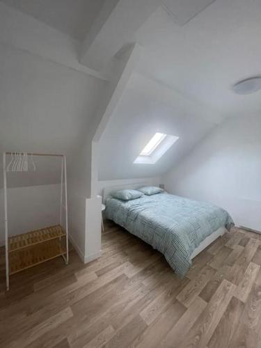a white bedroom with a bed and a wooden floor at L'Impasse Maison avec Jardin in Isbergues