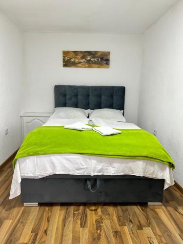 a bedroom with a large bed with a green blanket at Apartman MIA in Travnik