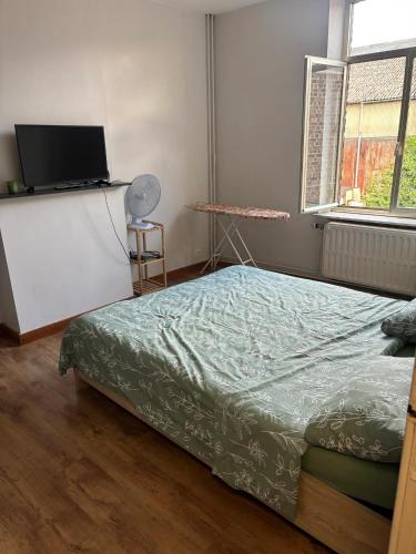 TilleurにあるCharming House in Sclessin, Liège with Terraceのベッドとテレビ付きの机のある寝室