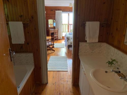 a bathroom with a tub and a sink in a room at Bay View Cabin in Gordonʼs Bay
