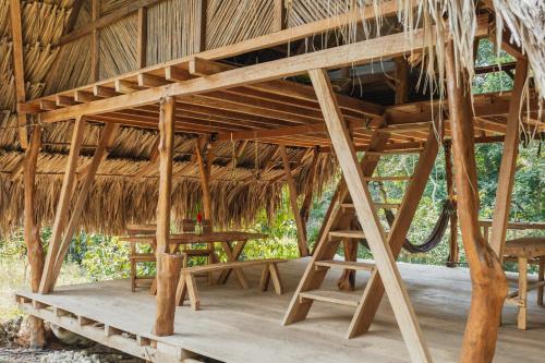 a large thatched hut with a table and benches at La Ponderosa Reserve in Buritaca
