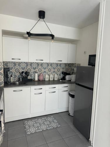 une cuisine avec des armoires blanches et un réfrigérateur noir dans l'établissement La Fleur de Montmagny, à Montmagny
