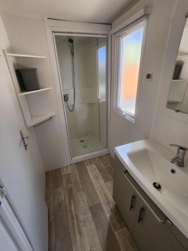 une salle de bain blanche avec une douche et un lavabo dans l'établissement Bungalow confort dans Camping 4 étoiles Marina de Canet Front de mer, à Canet