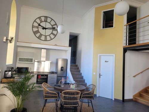 une cuisine avec une table, des chaises et une horloge dans l'établissement L'instant des Plaisirs, à Héming