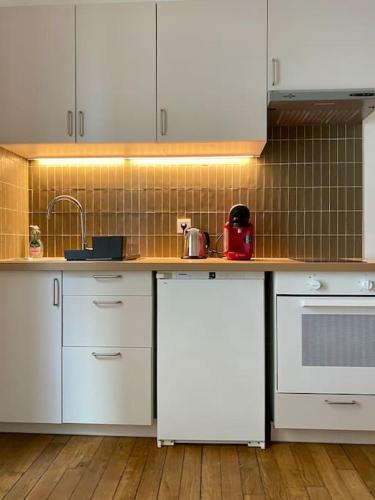 une cuisine avec des armoires blanches et un comptoir dans l'établissement Appartement - Proche Paris - Stade de France, à Saint-Denis