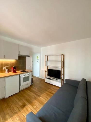 un salon avec un canapé bleu et une cuisine dans l'établissement Appartement - Proche Paris - Stade de France, à Saint-Denis