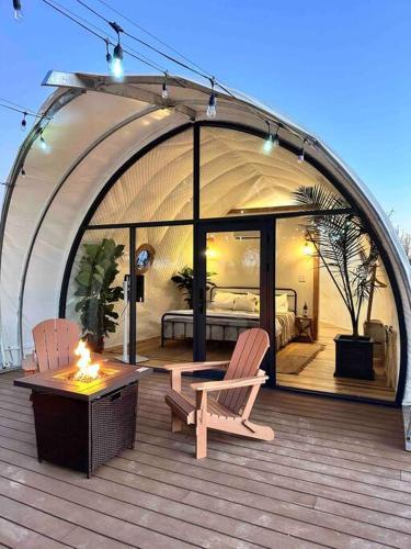 a patio with two chairs and a bed in a tent at The Cokoon at the Retreat in Fredericksburg