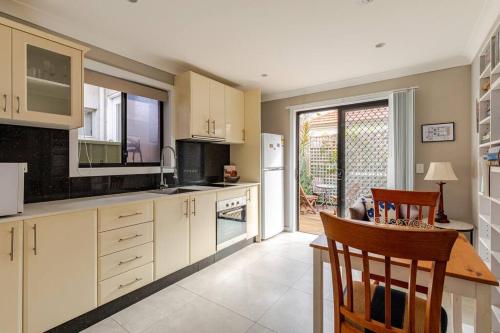 a kitchen with white cabinets and a table and chairs at New granny flat in Narwee in Narwee