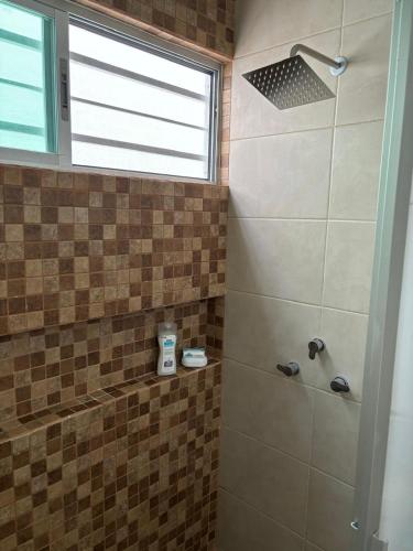a bathroom with a shower with a window at In Wotoch in Cancún