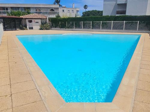 une grande piscine bleue dans une cour dans l'établissement Appartement bord de mer, piscine, à Villeneuve-Loubet