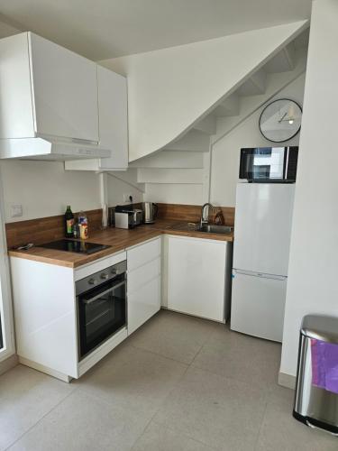 une cuisine avec des armoires blanches, un évier et un réfrigérateur dans l'établissement TERRASSE La Varenne, à Saint-Maur-des-Fossés