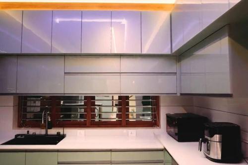 a kitchen with white cabinets and a sink at Luxurious 5000 SQFT Mansion with Modern Comforts And Spacious Elegance in Malappuram