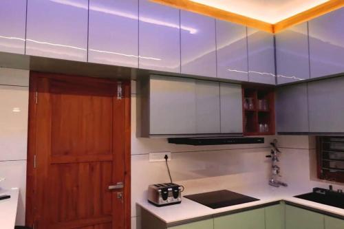 a kitchen with white and wooden cabinets and a counter top at Luxurious 5000 SQFT Mansion with Modern Comforts And Spacious Elegance in Malappuram