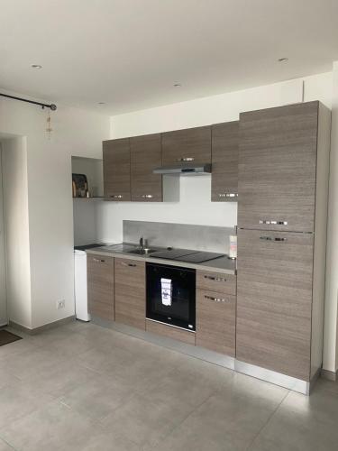 - une cuisine avec des placards en bois et une cuisinière dans l'établissement Splendide Studio Miramar vue mer avec terrasse, à Bandol