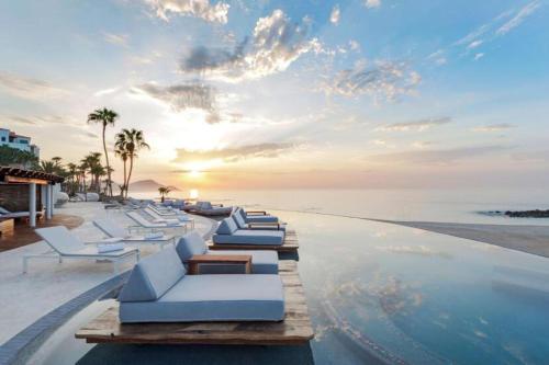 a row of white lounge chairs on a swimming pool at Beach&Golf suites in El Bedito