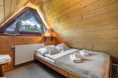 Una cama en una habitación de madera con ventana. en Szałas pod Szymoszkową, en Kościelisko
