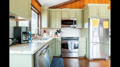a kitchen with green cabinets and stainless steel appliances at Beautiful Windham Chalet 2 minutes to the Mountain in Windham