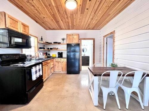 cocina con mesa y nevera negra en Little Haus on the Farm with a Hot Tub, en Fredericksburg