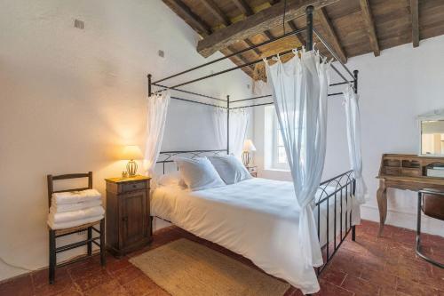 une chambre avec un lit à baldaquin et un bureau dans l'établissement Les Calades, à Lédenon