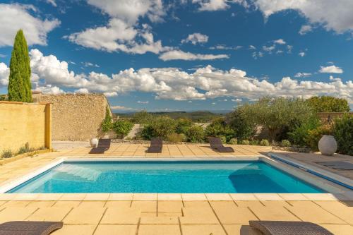 une piscine dans un jardin avec un ciel bleu dans l'établissement Les Calades, à Lédenon