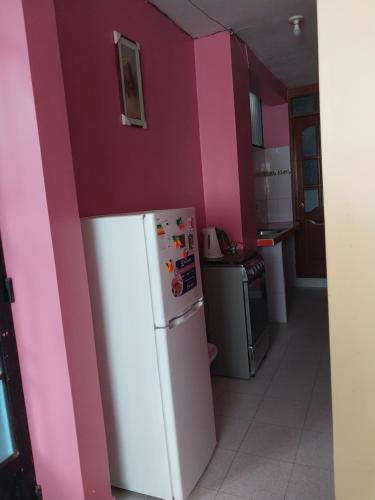 a kitchen with a white refrigerator and pink walls at Departamento 2 camas in Moyobamba
