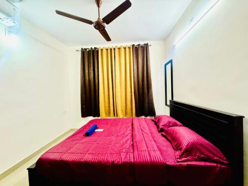 a bedroom with a pink bed with a ceiling fan at SERENE POND RETREAT KOWDIAR 4bhk apartment in Trivandrum