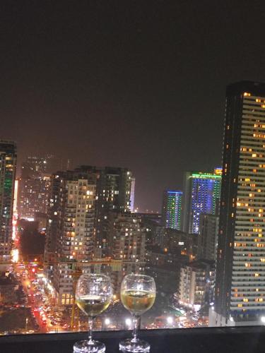 two wine glasses sitting on a ledge with a city skyline at Sea View Apartment in Batumi, Georgia in Angisa